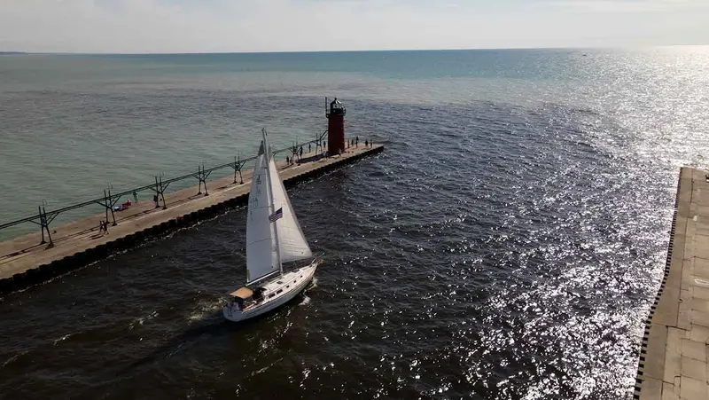 The Margaret Ann under sail beside the South Haven pier and its red lighthouse