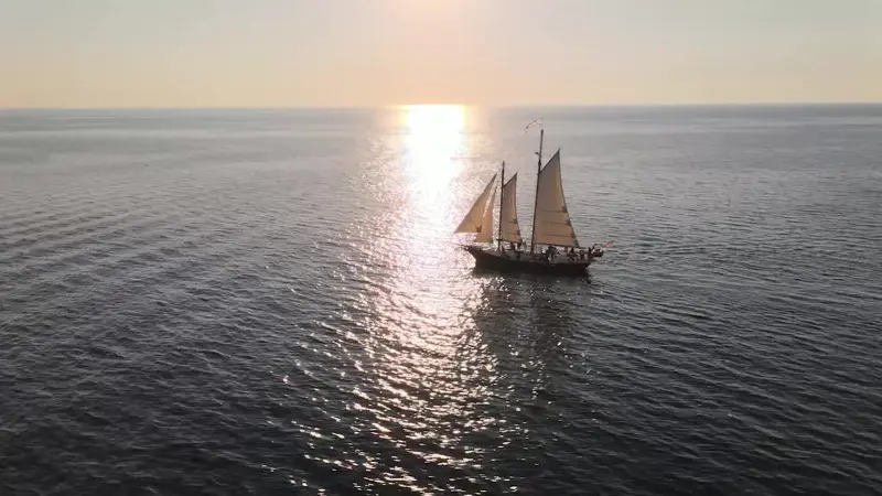 Serenity under sail on open water, the low sun glittering on the lake